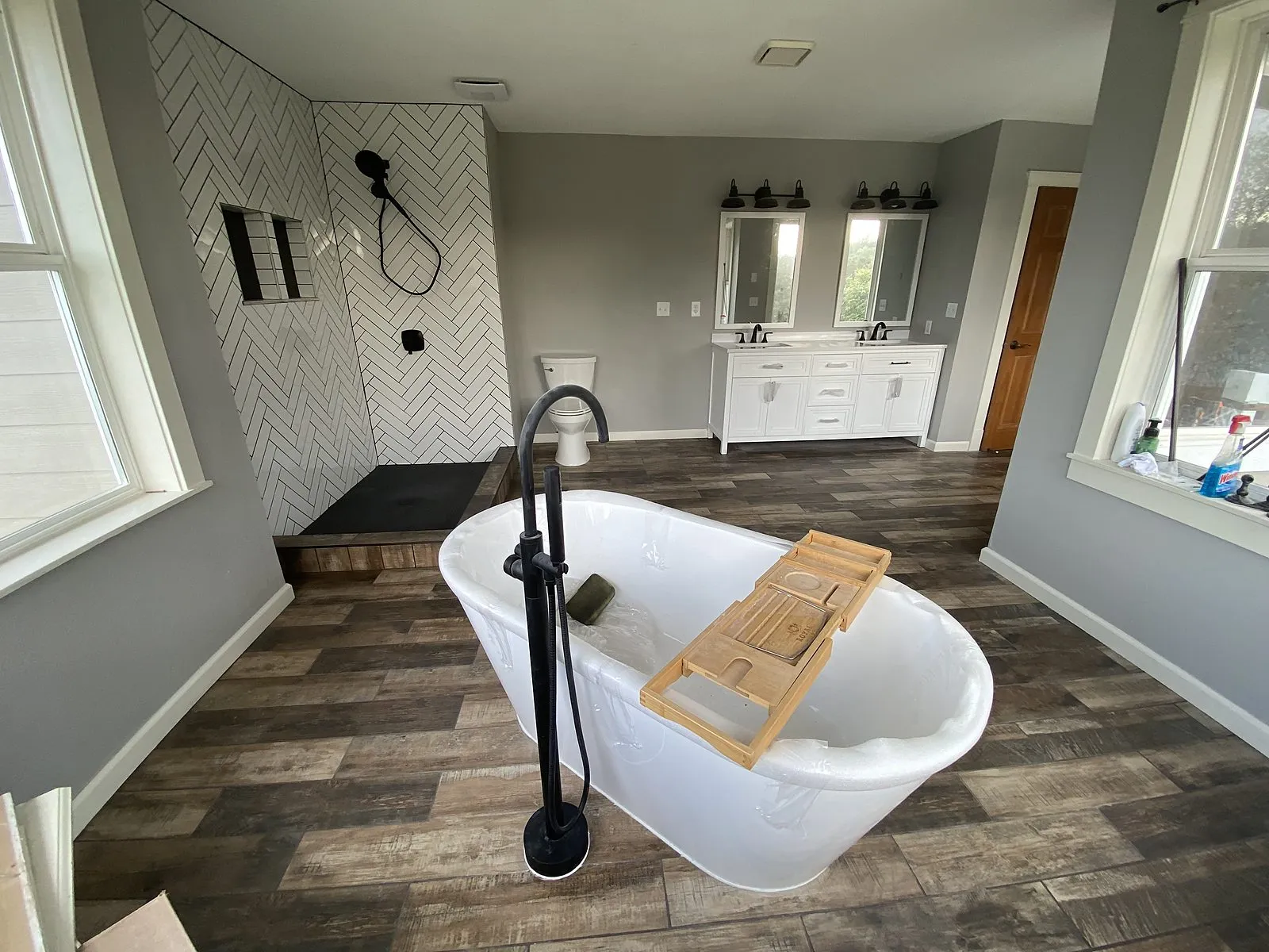 A master bathroom with a freestanding tub, herringbone tile shower and double vanity