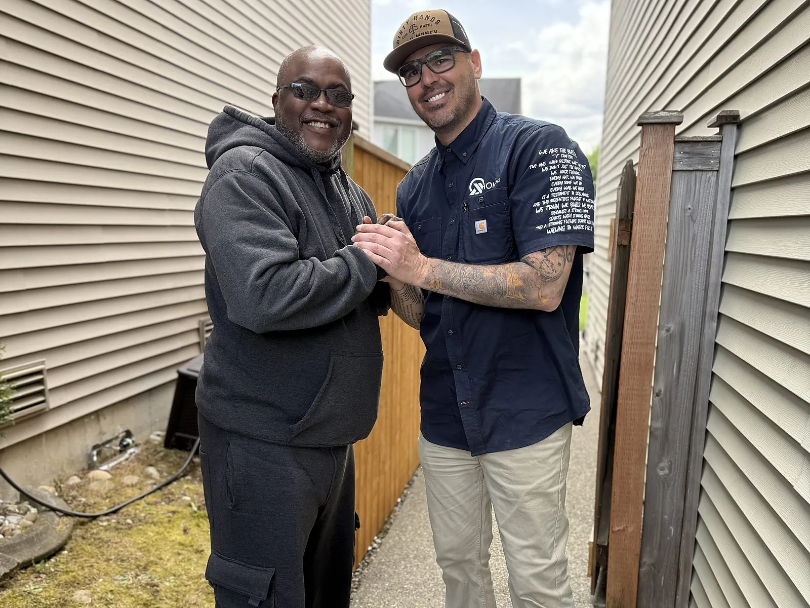 An All Home HX team member shaking hands with a homeowner outside their home