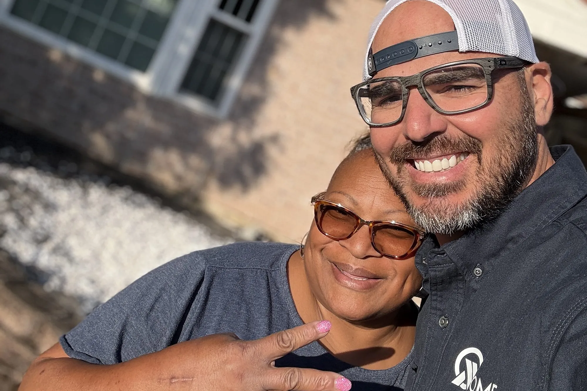 An All Home HX team member and a homeowner smiling together outside her home