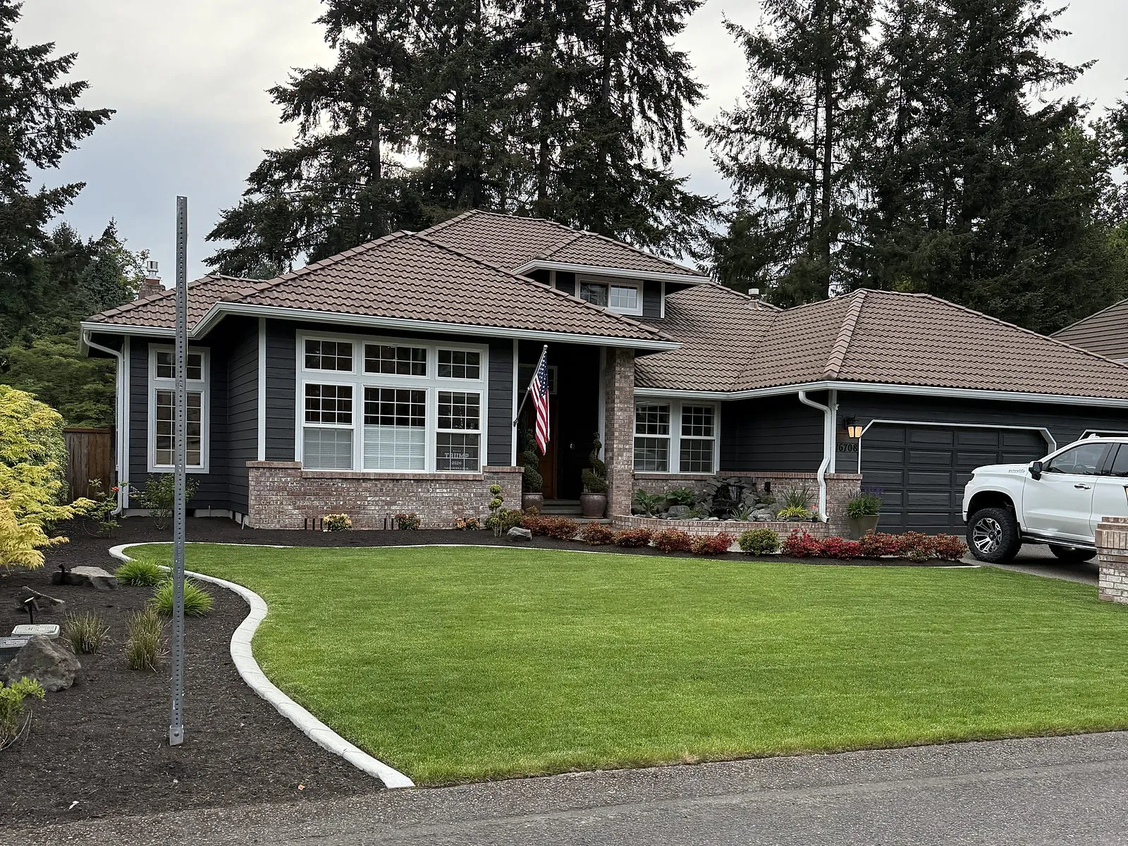 A freshly painted home exterior with a manicured lawn and brick accents