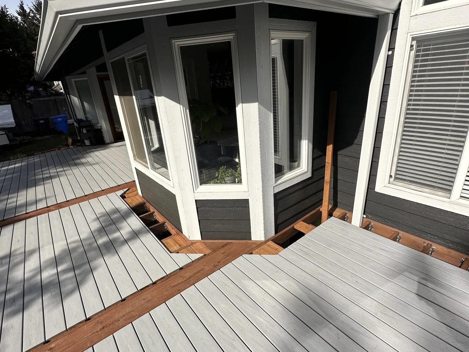 A bay window bump-out with new white windows and gray siding