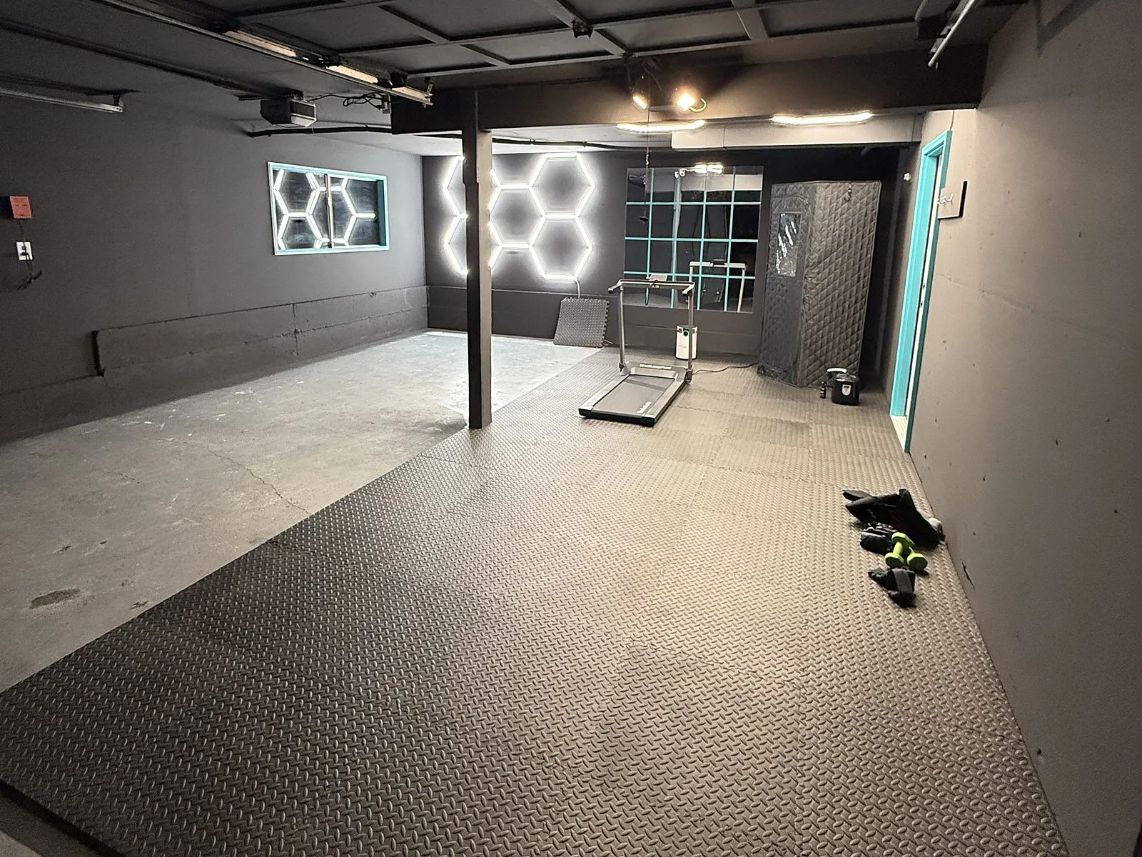 A finished garage conversion with dark walls, a diamond-plate floor and LED strip lighting