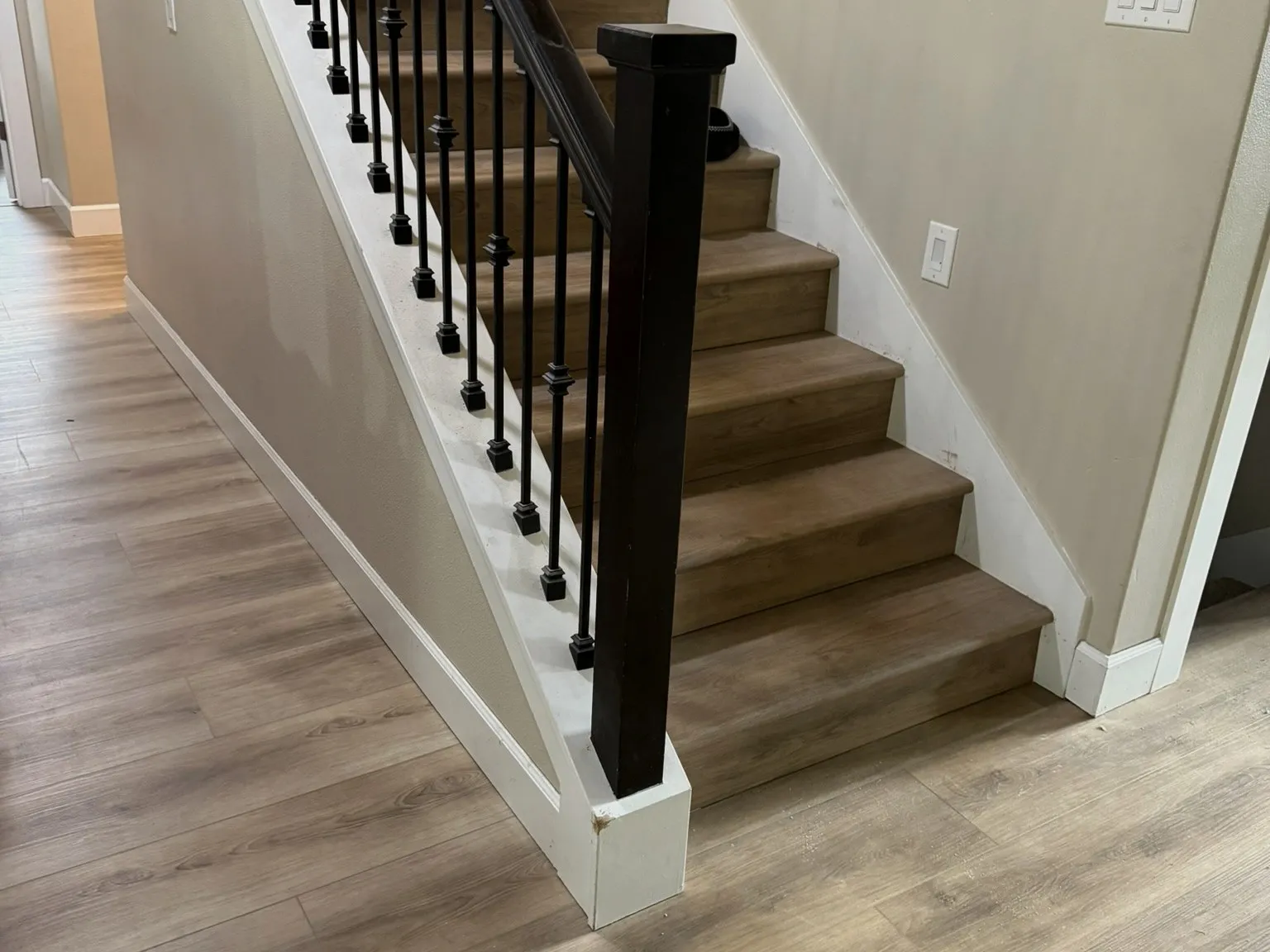 A finished staircase with wood treads, white risers and black metal balusters