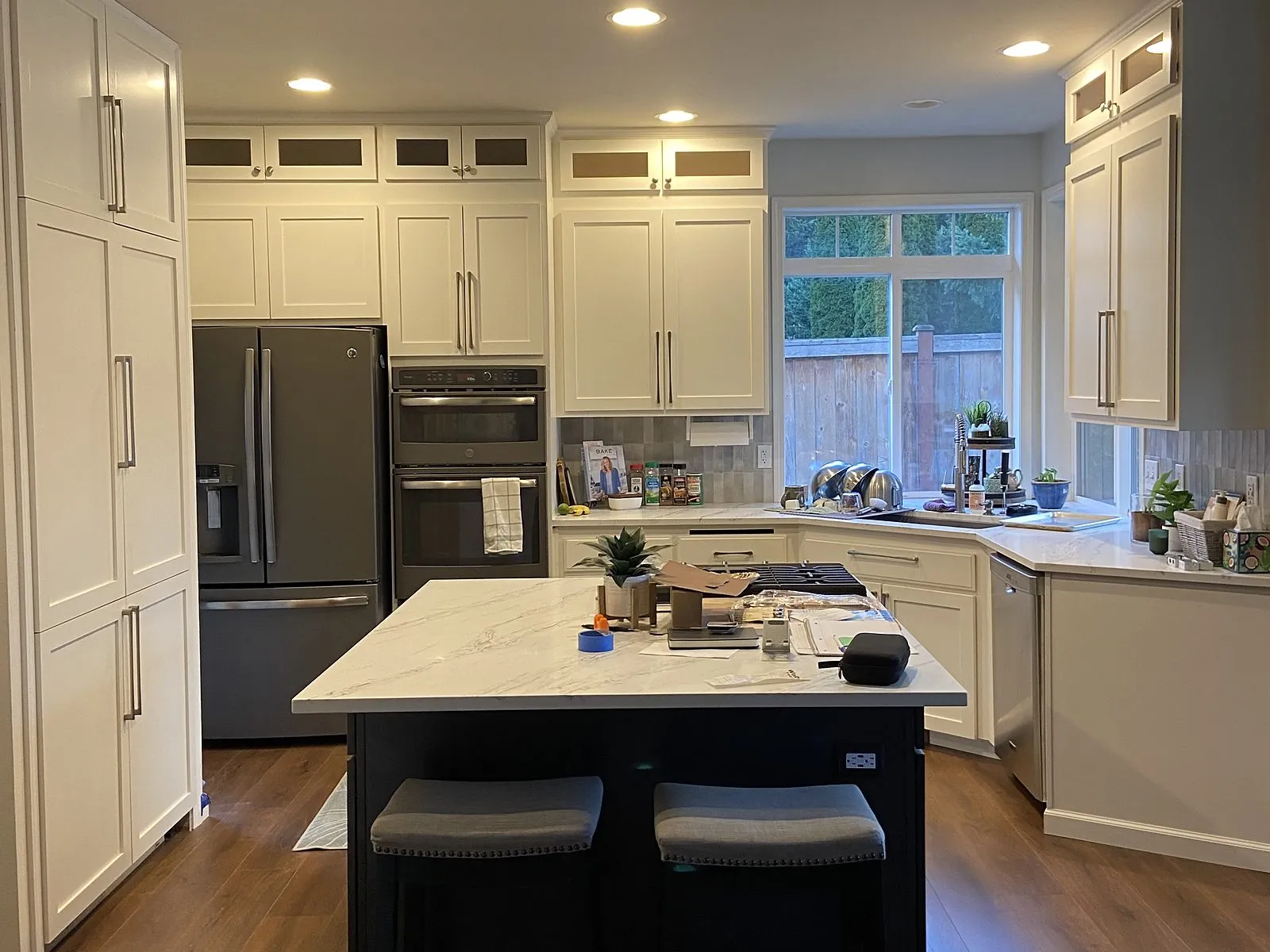 A kitchen with white shaker cabinets to the ceiling and a navy island with seating